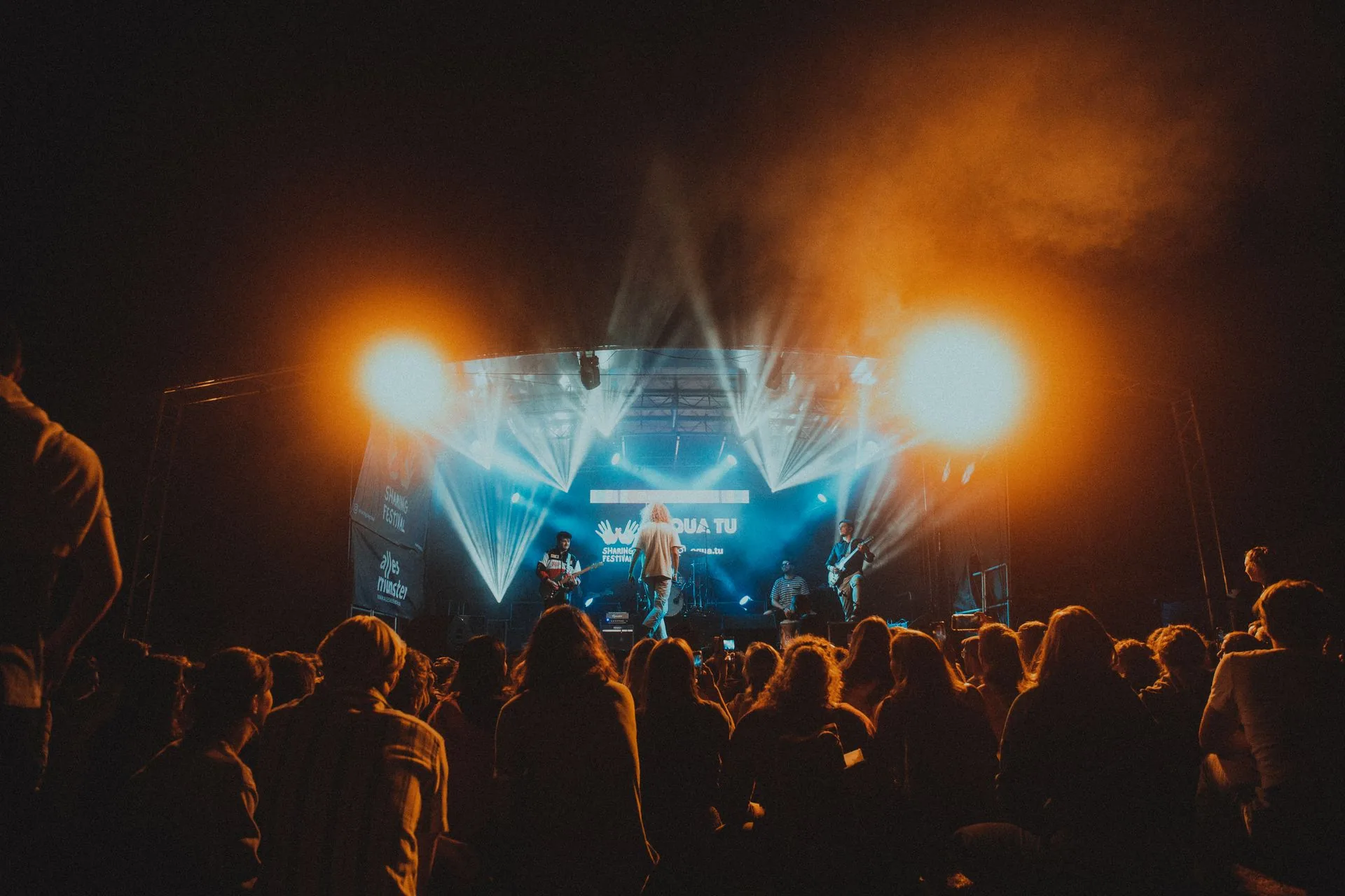 A live stage, seen from the crowd, at night